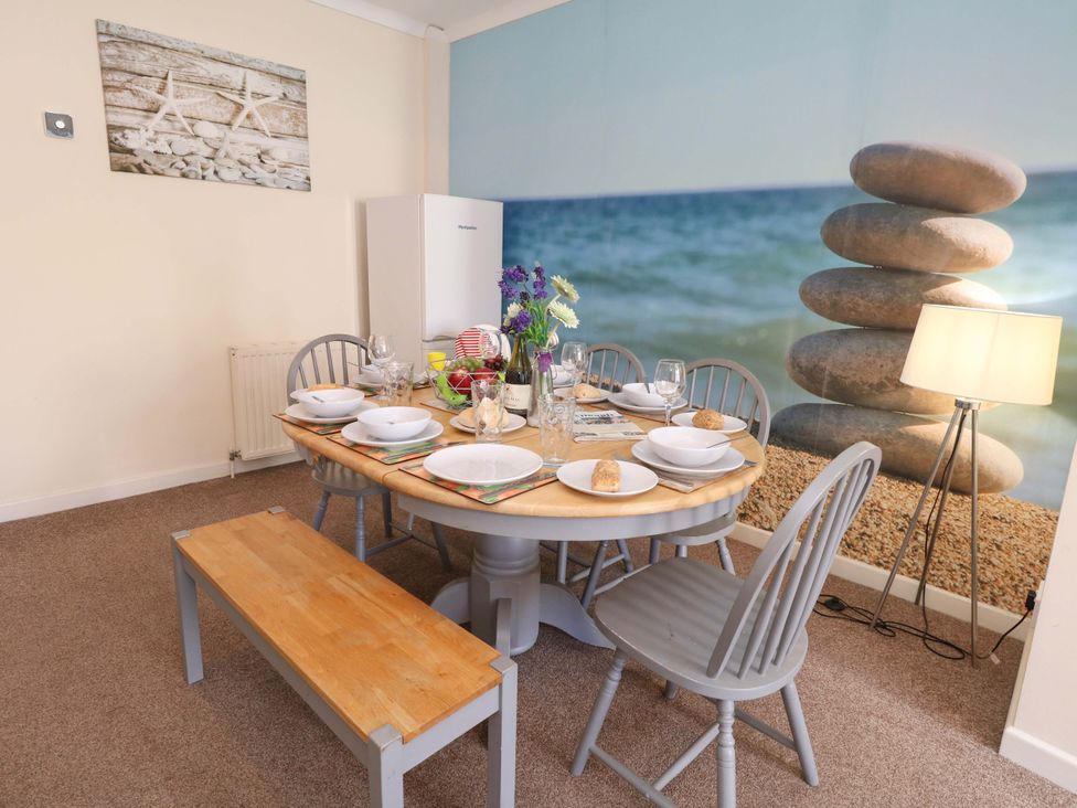 A dining room with a round table set for a meal at Home from Home near the Sea Weymouth