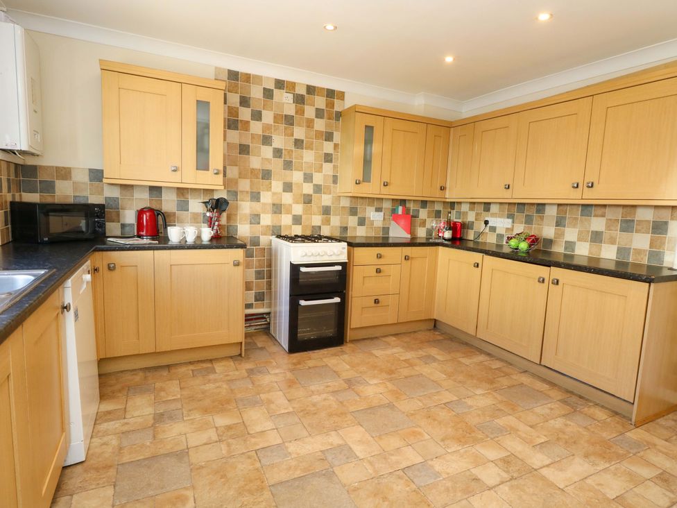 A kitchen with wooden cabinets and basic appliances at Home from Home near the Sea in Weymouth