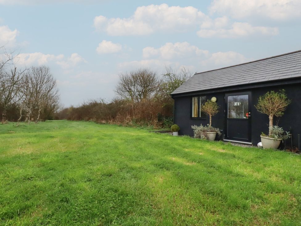 A cottage with planters and grass in the outdoor area at Little Hallegan in Camborne