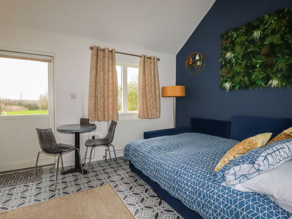 A bedroom with a bed, table and chairs at Little Hallegan in Camborne