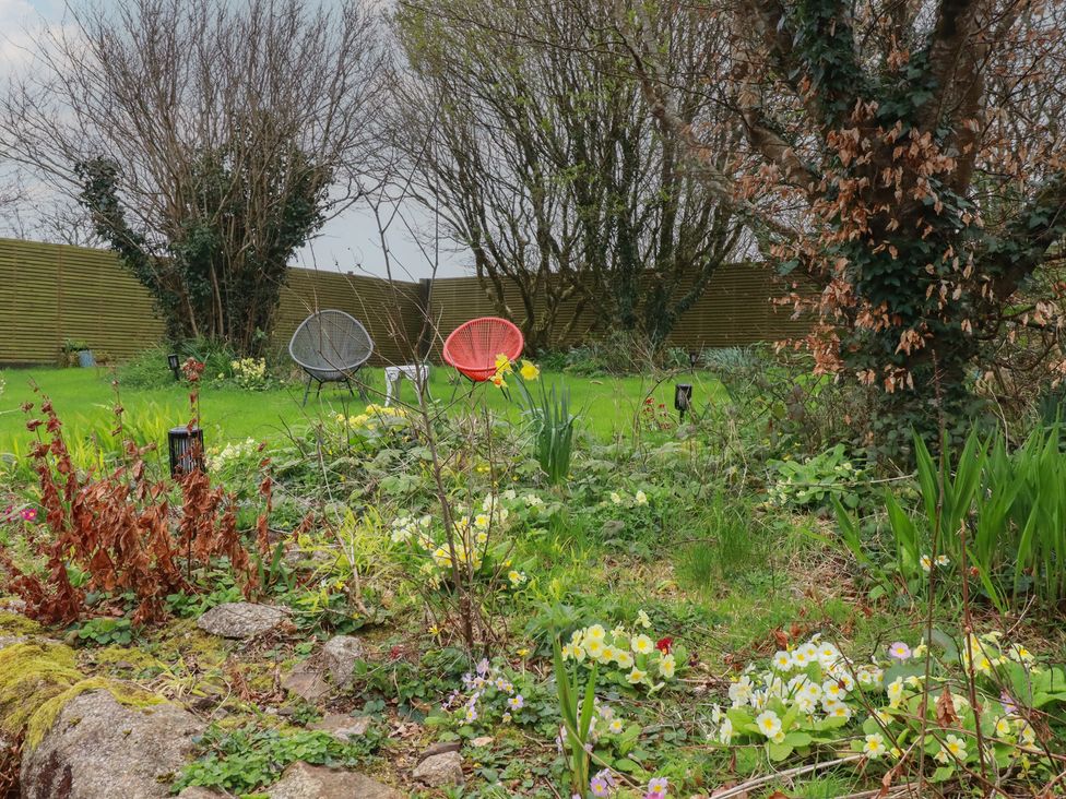 A garden with two chairs and flowers at Little Hallegan in Camborne