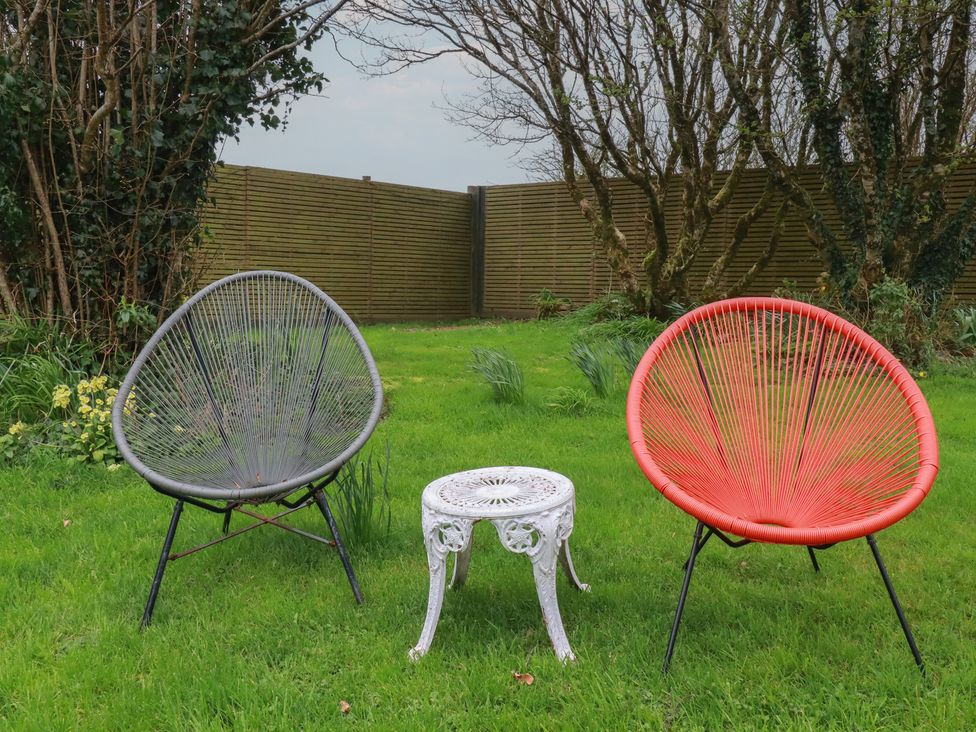 A garden with two acapulco chairs and a coffee table at Little Hallegan in Camborne