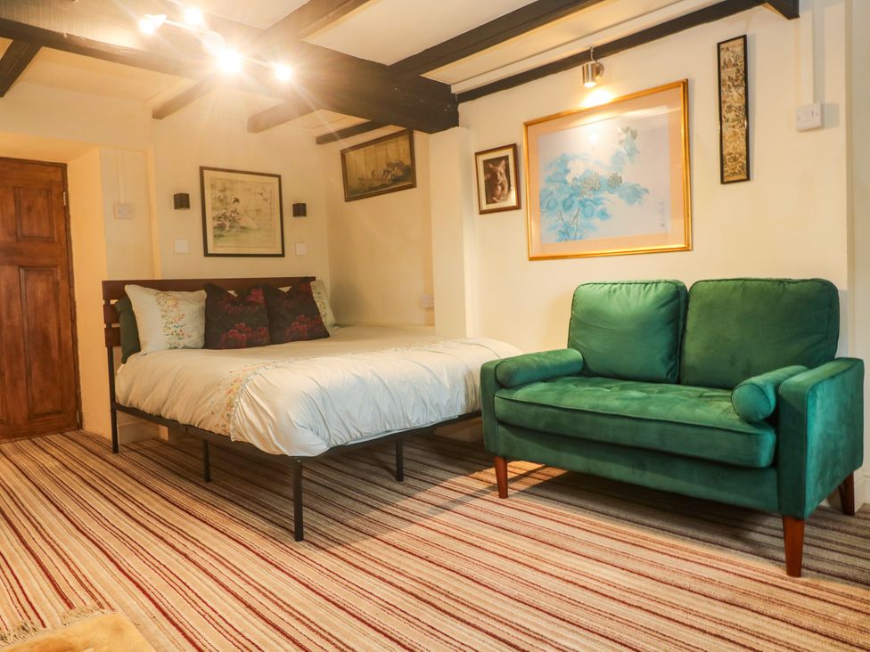 A bedroom with a bed and a green sofa at Ninevah Lelant