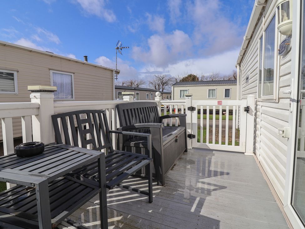 A deck area with chairs and a table at Carvan CP10 in Prestatyn