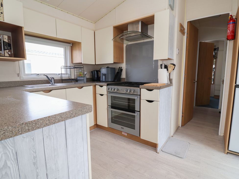 A kitchen with cabinets, sink, and oven at Carvan CP10 in Prestatyn