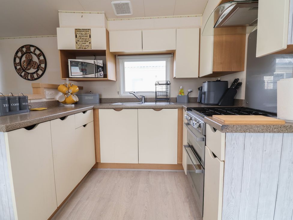 A kitchen with cabinets, sink, microwave, and stove at Carvan CP10 Prestatyn