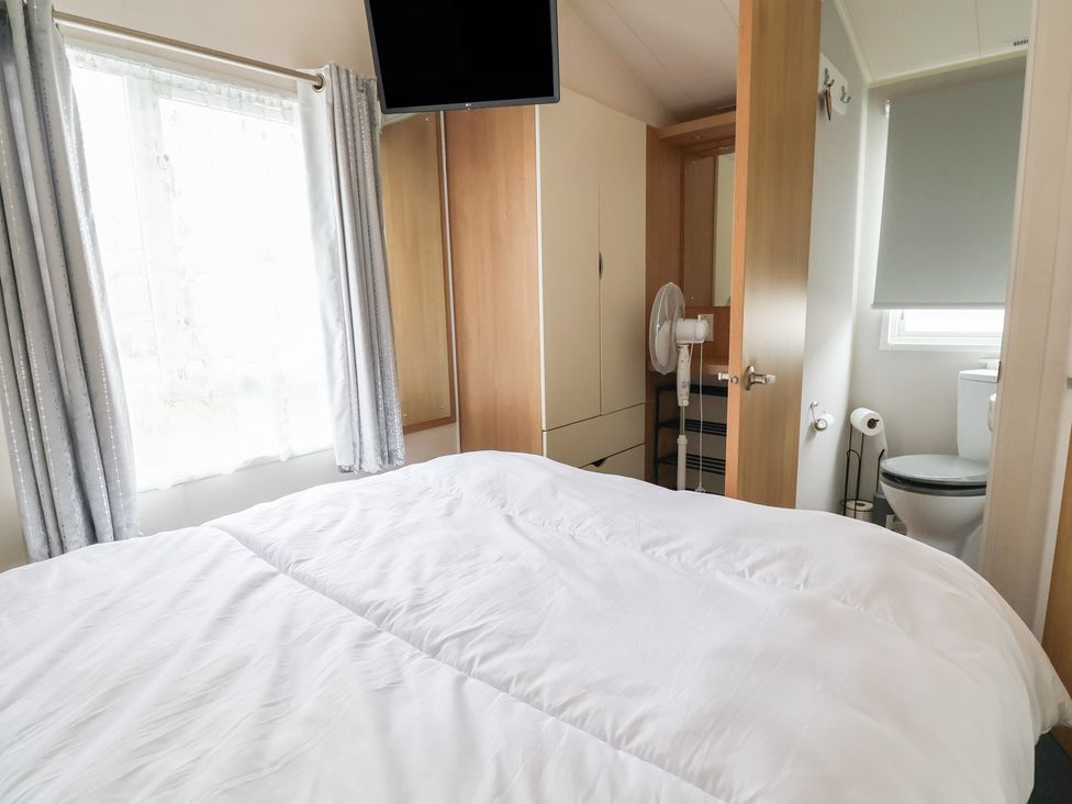 A bedroom with a bed and a television at Carvan CP10 Prestatyn