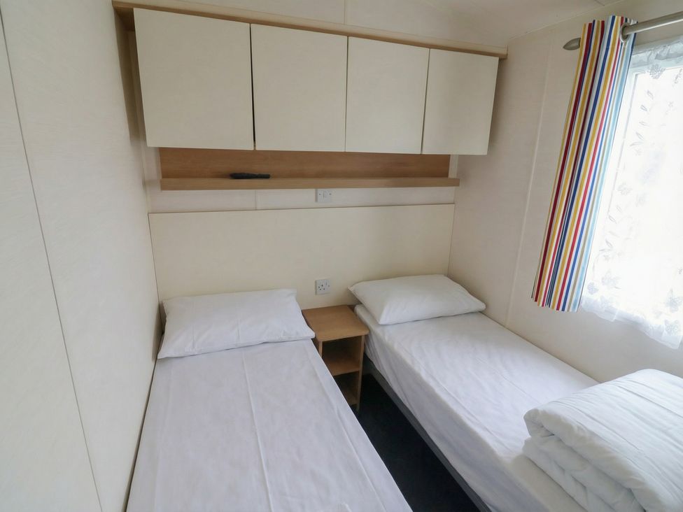 A bedroom with two beds and a window at Carvan CP10 in Prestatyn
