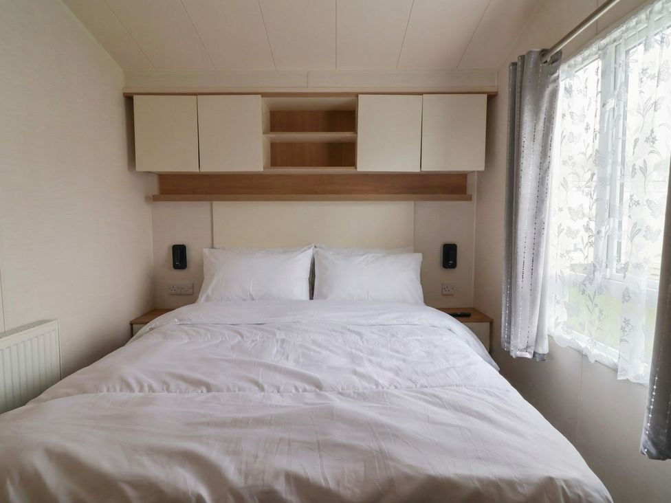 A bedroom with a bed and cabinets at Carvan CP10 Prestatyn