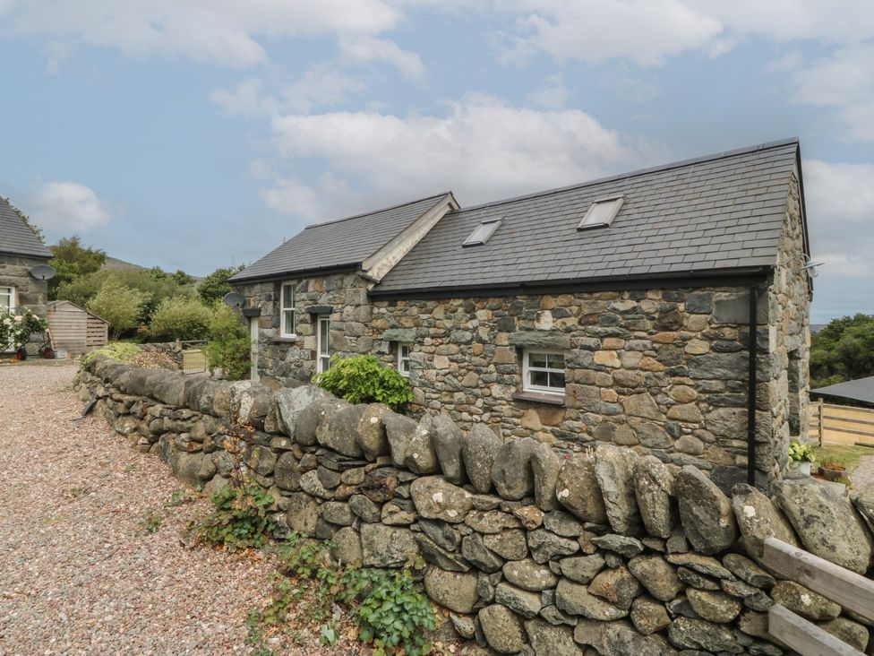 A stone house with a rock wall and garden at The Byre Conwy