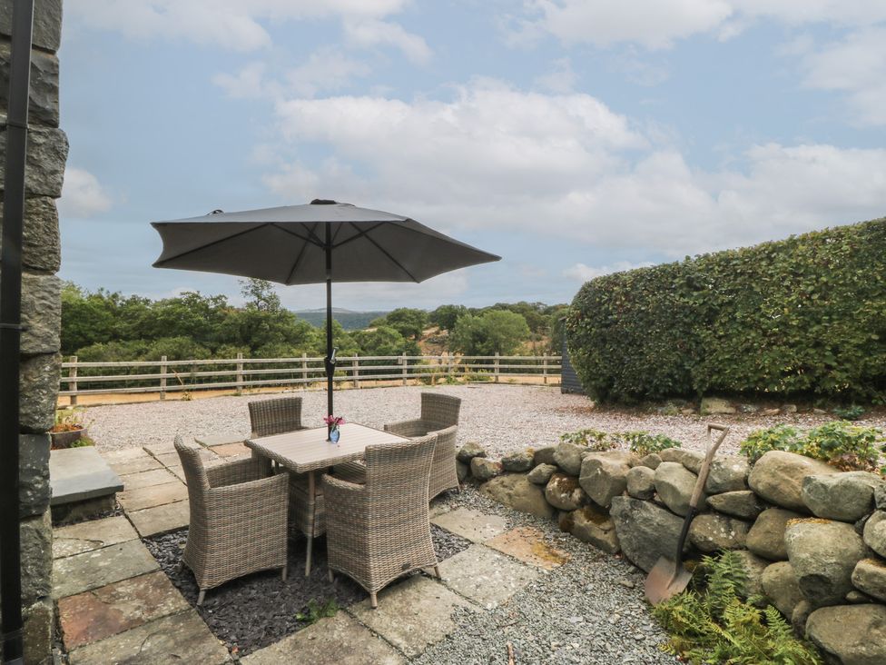 A patio with a table and chairs under an umbrella at The Byre in Conwy