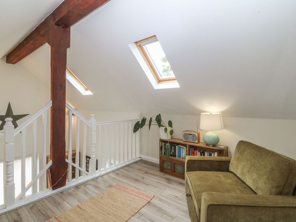 A snug with a sofa and bookshelves at The Byre in Conwy