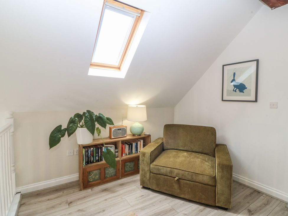 A snug with an armchair and bookshelf at The Byre in Conwy