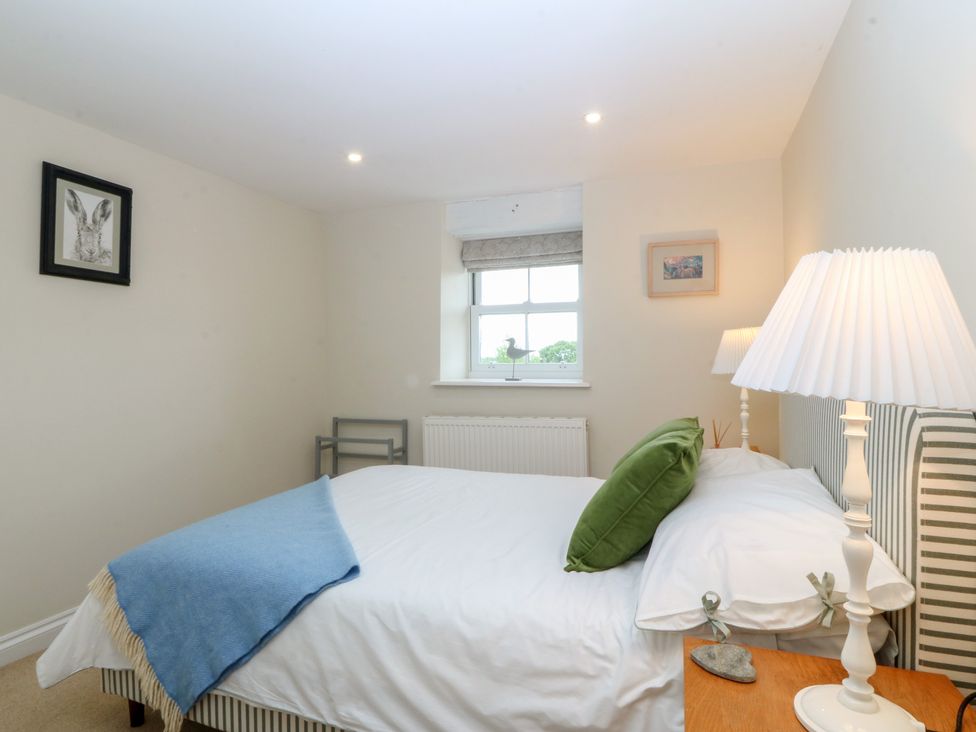 A bedroom with a bed and lamp at The Byre in Conwy