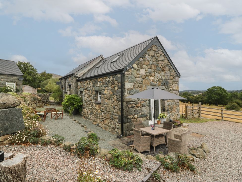 An outdoor area with a stone building and seating at The Byre in Conwy