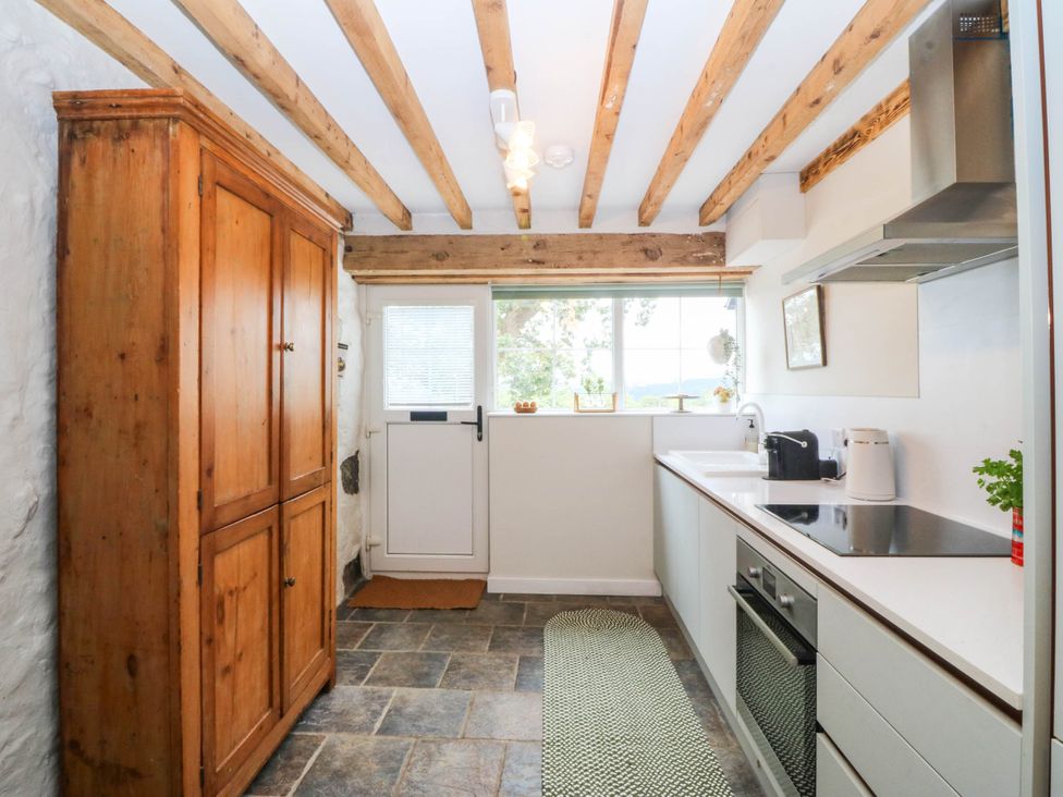 A kitchen with a cupboard, stove, and sink at Little Oak near Tal-Y-Bont