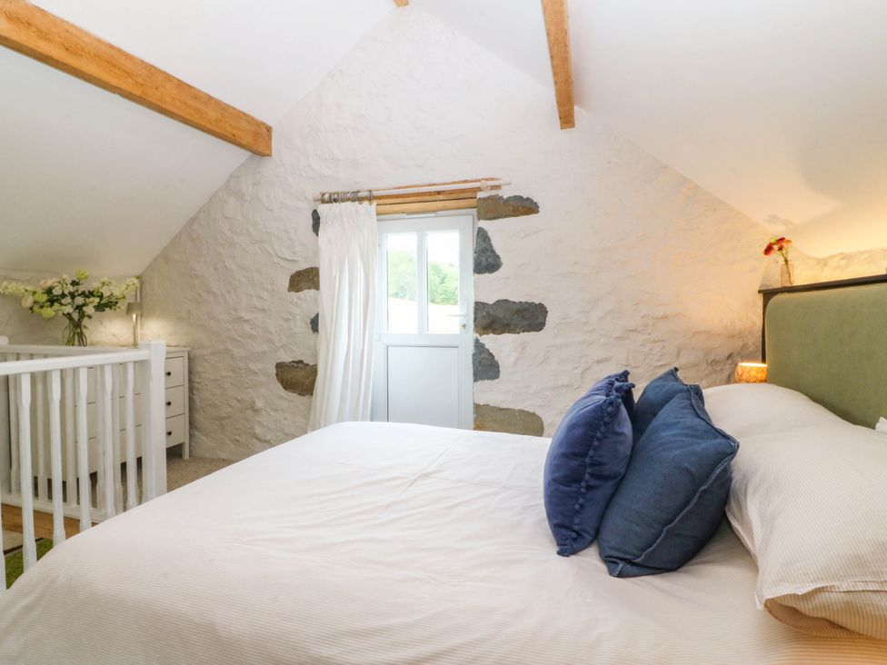 A bedroom with a bed, window, dresser and flowers at Little Oak near Tal-Y-Bont