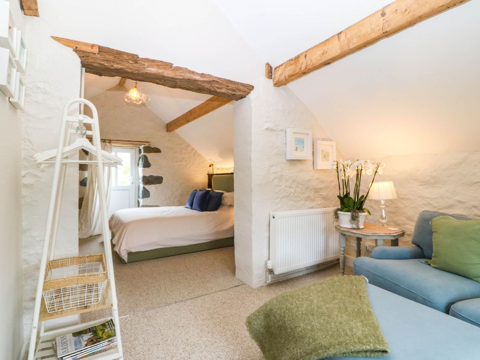 A bedroom with a bed, chair, and lamp at Little Oak near Tal-Y-Bont