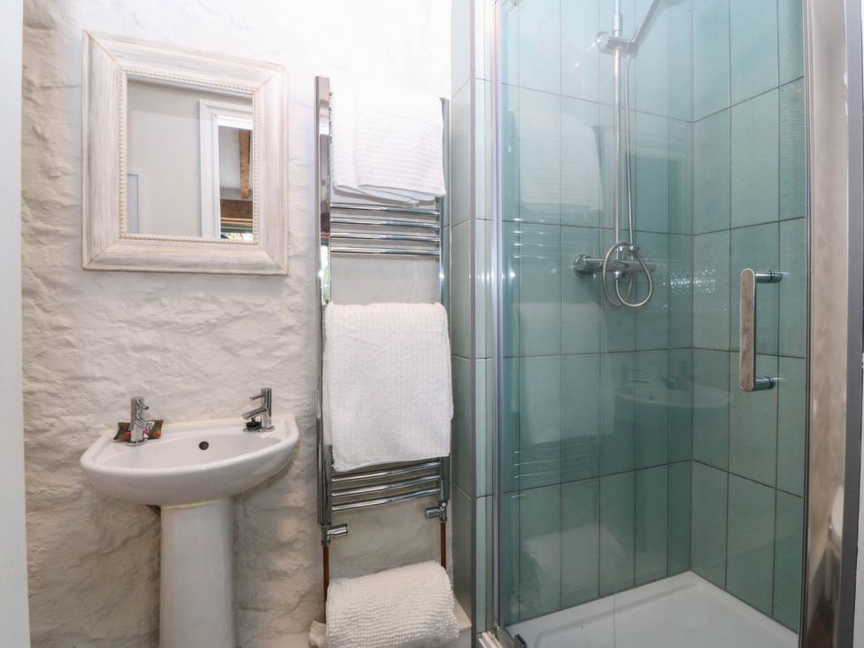 A bathroom with a sink, shower stall, towel rail, and mirror at Little Oak near Tal-Y-Bont