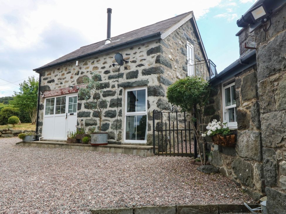 An outdoor view of a stone house with a gate and gravel path at Little Oak near Tal-Y-Bont