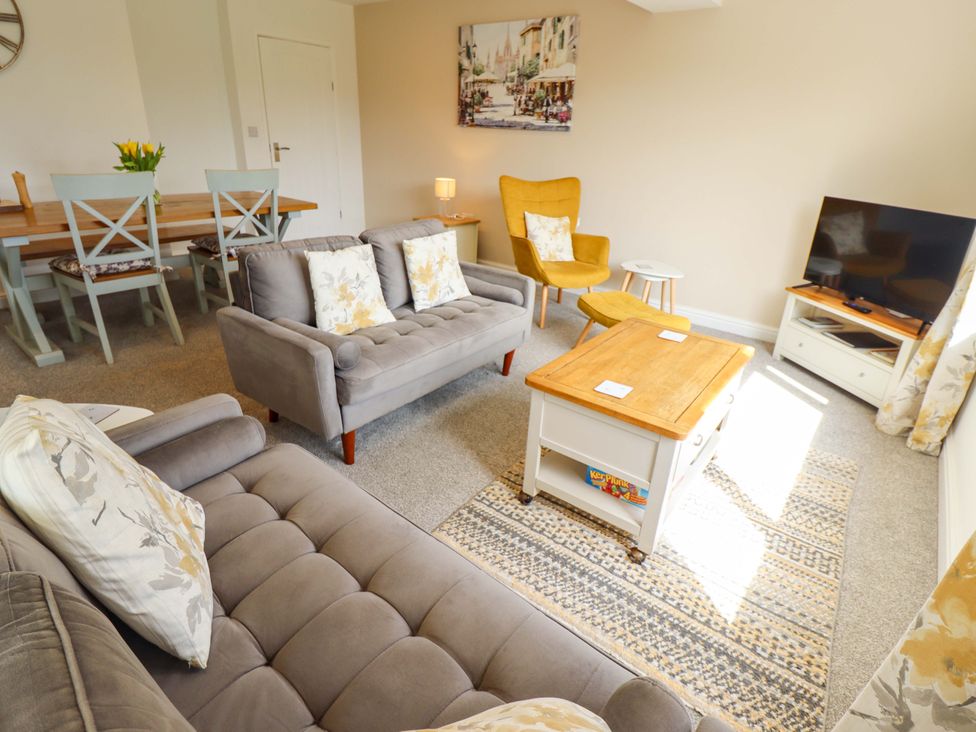 A living room with a sofa, armchair, coffee table, and television at Field View in North Walsham