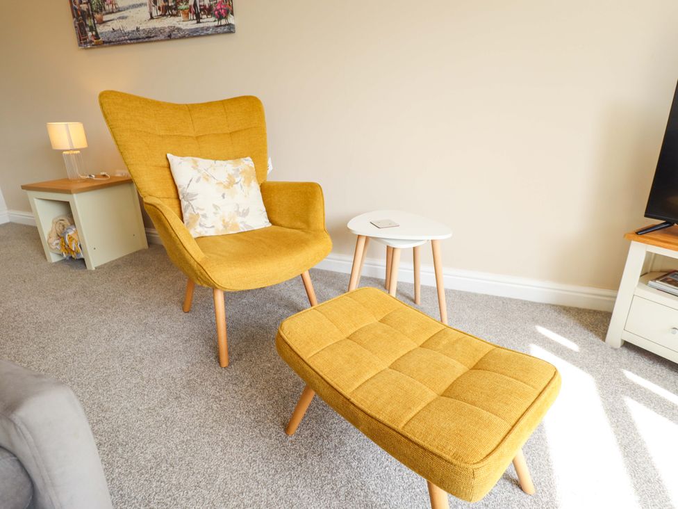 A living room with an armchair and an ottoman at Field View in North Walsham