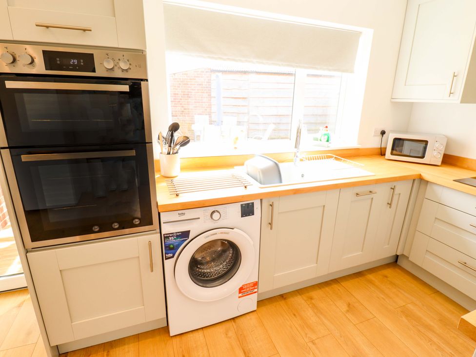 A kitchen with appliances including an oven, washing machine, and sink at Field View in North Walsham
