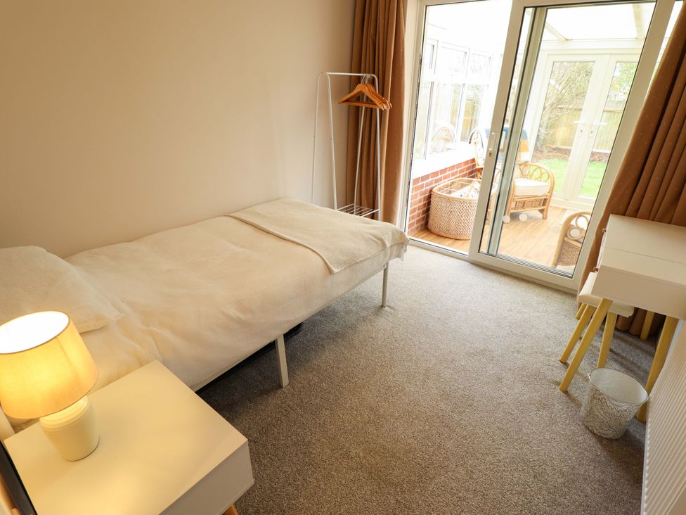 A bedroom with a single bed and a door leading to a conservatory at Field View North Walsham