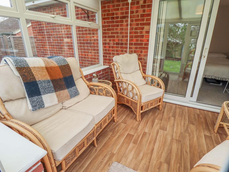 A conservatory with seating and a door at Field View in North Walsham