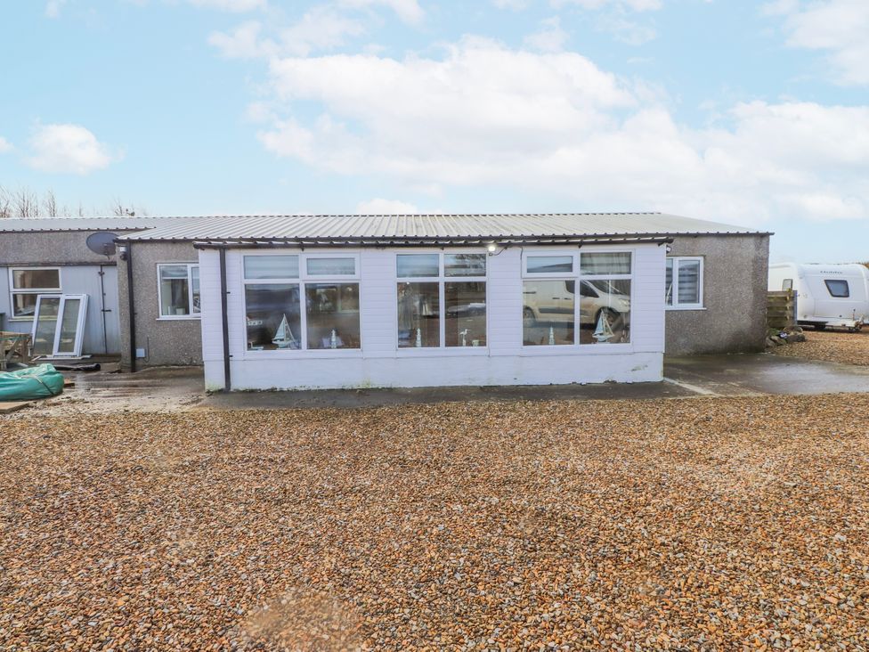 An outdoor view of a building with windows and gravel at Hen Fecws, Rhoshirwaun near Sarn Meyllteyrn