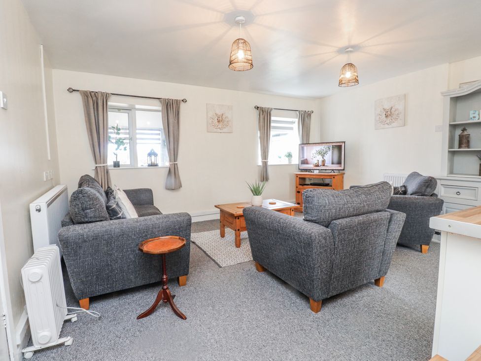 A living room with sofa, table, and television at Hen Fecws near Rhoshirwaun