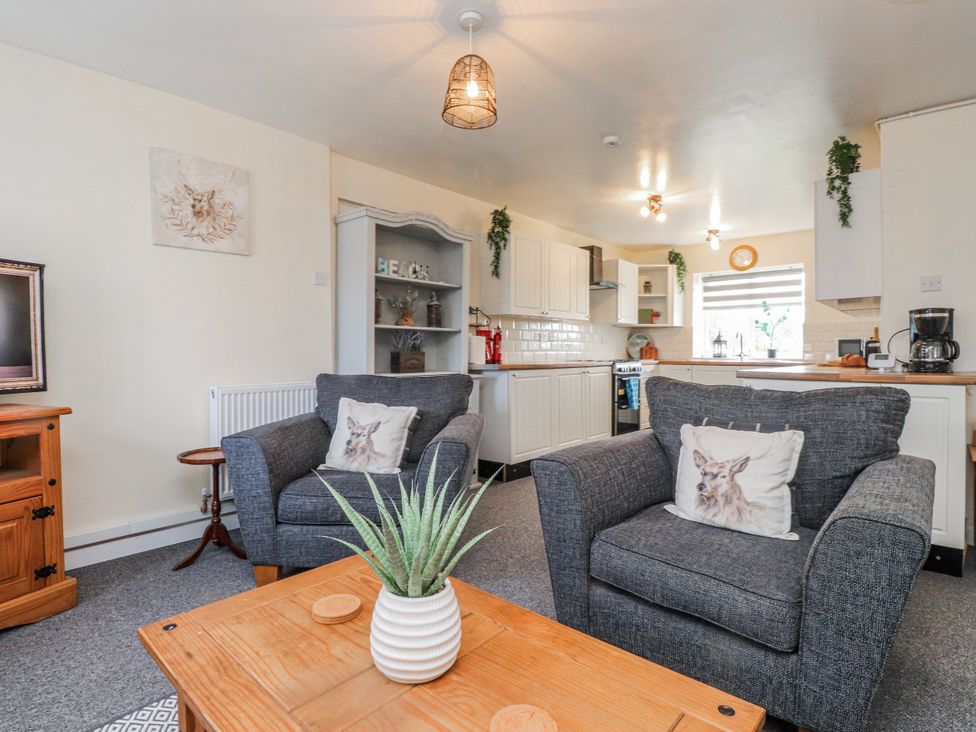 A living room with a coffee table and kitchen area at Hen Fecws in Rhoshirwaun near Sarn Meyllteyrn