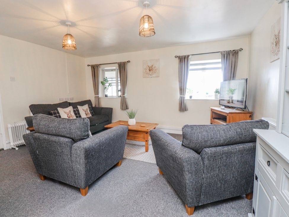A living room with a sofa, coffee table, and television at Hen Fecws Rhoshirwaun near Sarn Meyllteyrn