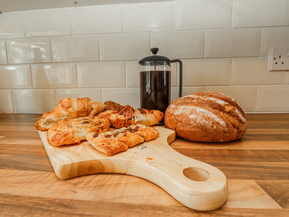 A cutting board with pastries and bread in a kitchen at Hen Fecws Rhoshirwaun near Sarn Meyllteyrn