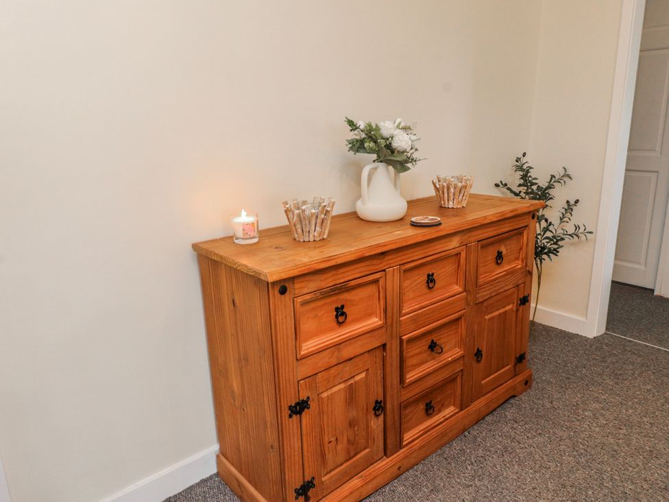 A wooden sideboard with a candle and a flower vase in a hallway at Hen Fecws Rhoshirwaun near Sarn Meyllteyrn