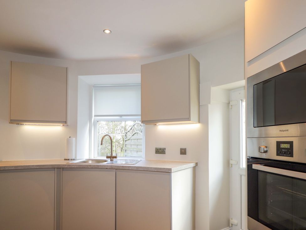 A kitchen with cabinets and appliances at Craig Cottage in Banff