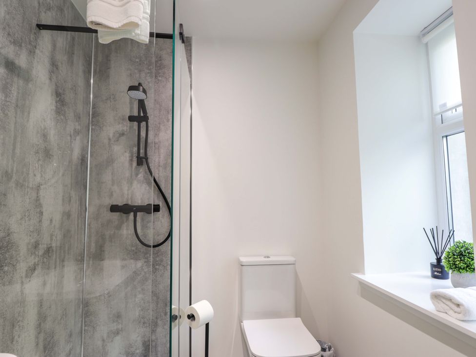 A bathroom with a shower, toilet, and sink at Craig Cottage in Banff