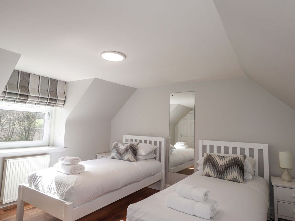 A bedroom with two beds and a mirror at Craig Cottage in Banff