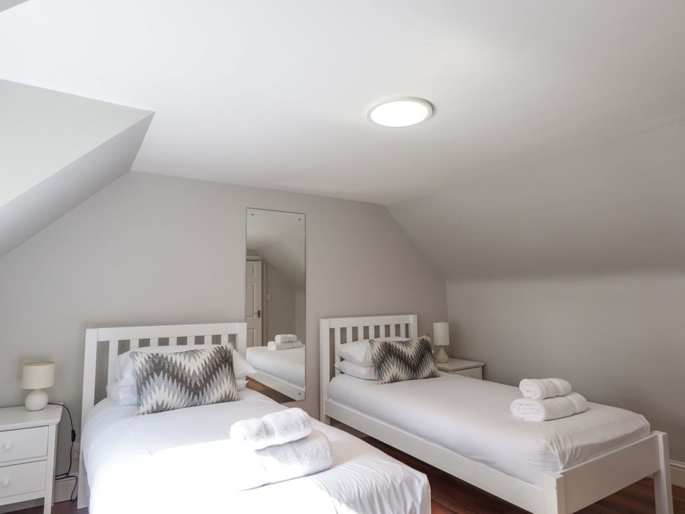 A bedroom with two beds and a mirror at Craig Cottage in Banff