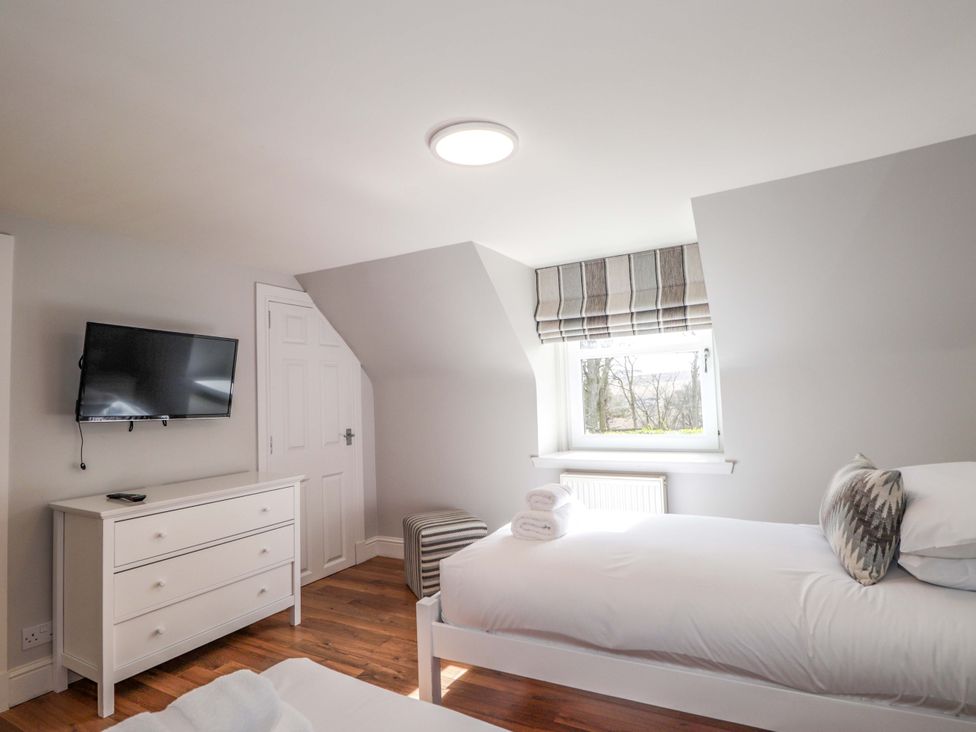 A bedroom with a bed and television at Craig Cottage in Banff