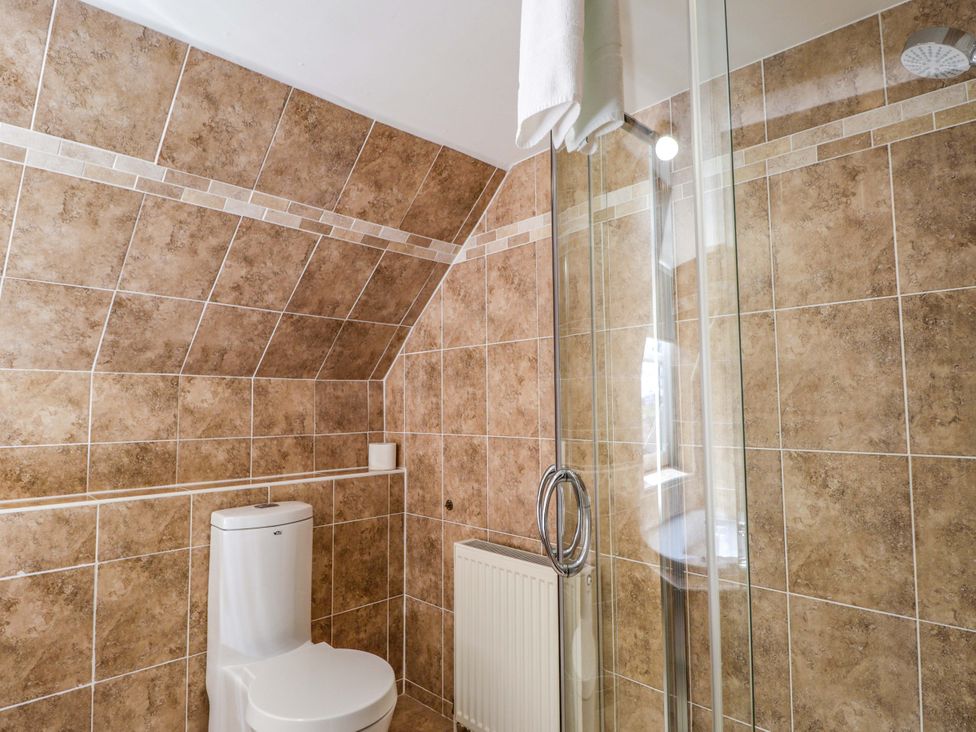 A bathroom with a shower, toilet, and radiator at Craig Cottage in Banff