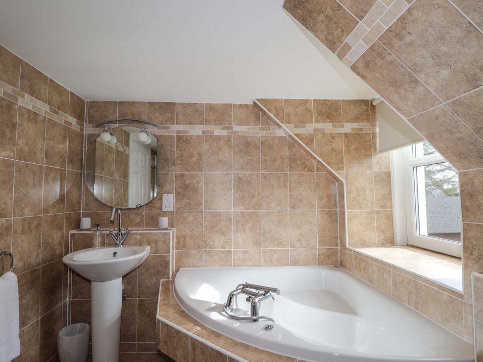 A bathroom with a bathtub, sink, and mirror at Craig Cottage in Banff