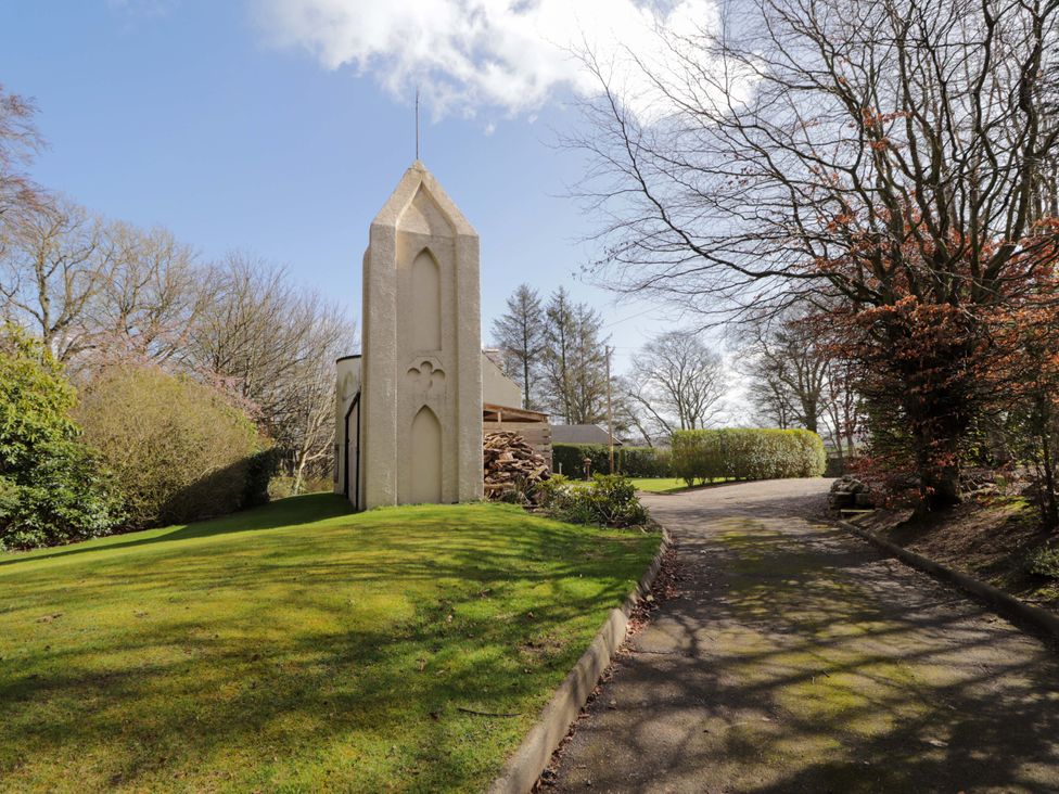A building surrounded by grass and trees at Craig Cottage in Banff