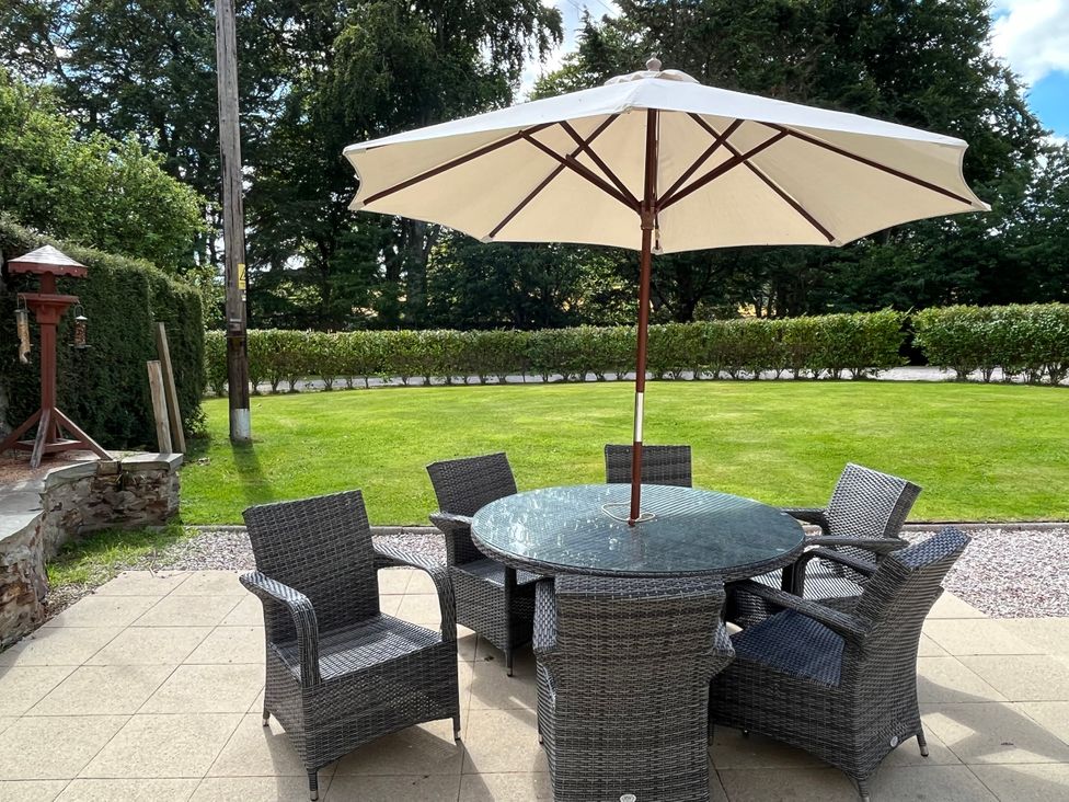 A patio with a table and chairs under an umbrella at Craig Cottage in Banff