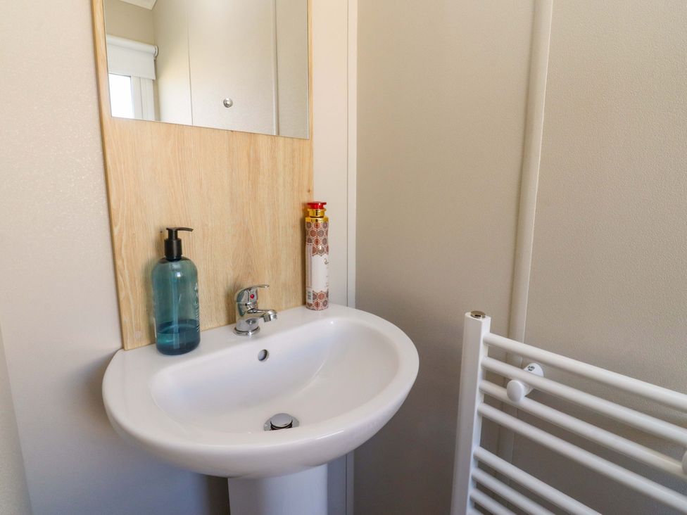 A sink with a mirror and soap dispenser in the bathroom at Plot B2 Crozzers Place Morecambe
