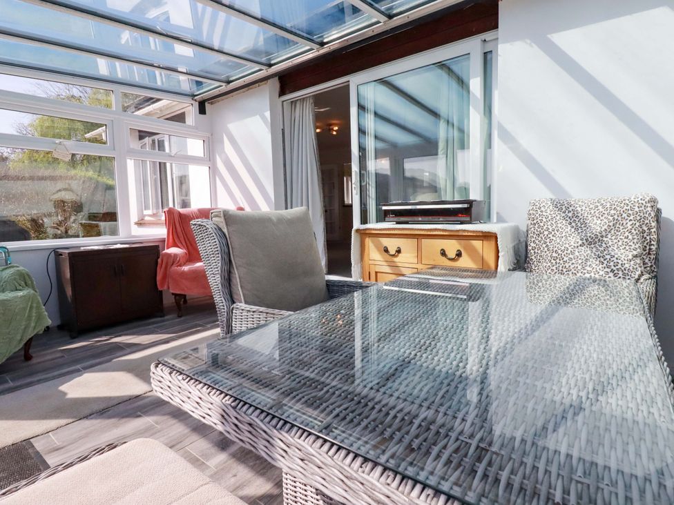 A conservatory with a glass roof and furniture at Tregoning in Lostwithiel