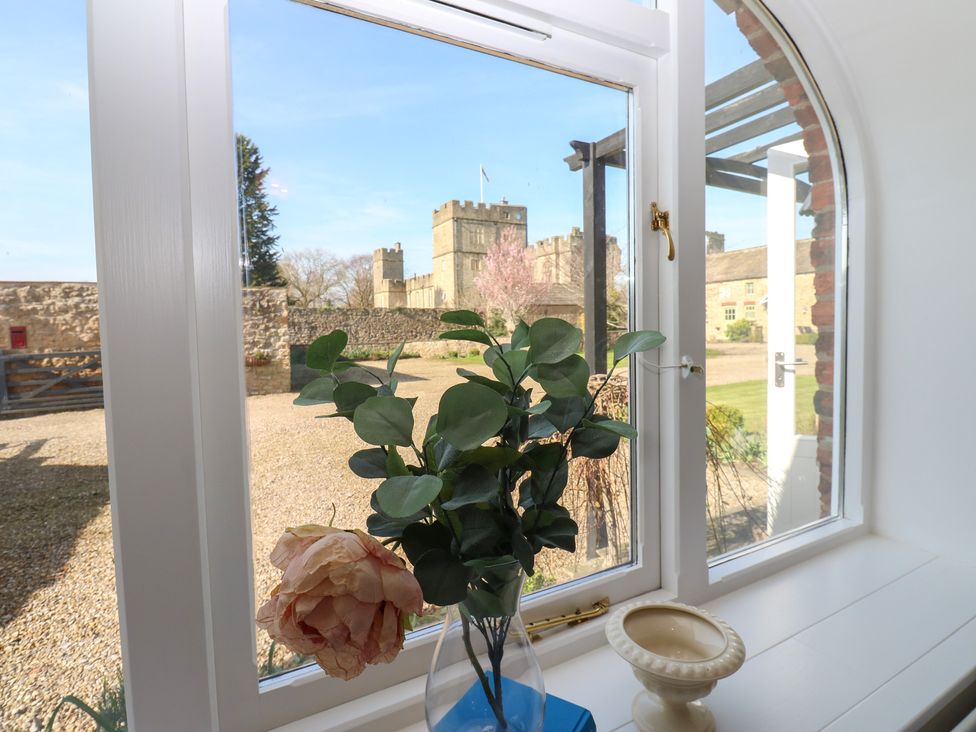 A window with flowers and a view of a castle at Castle View Cottage Bedale