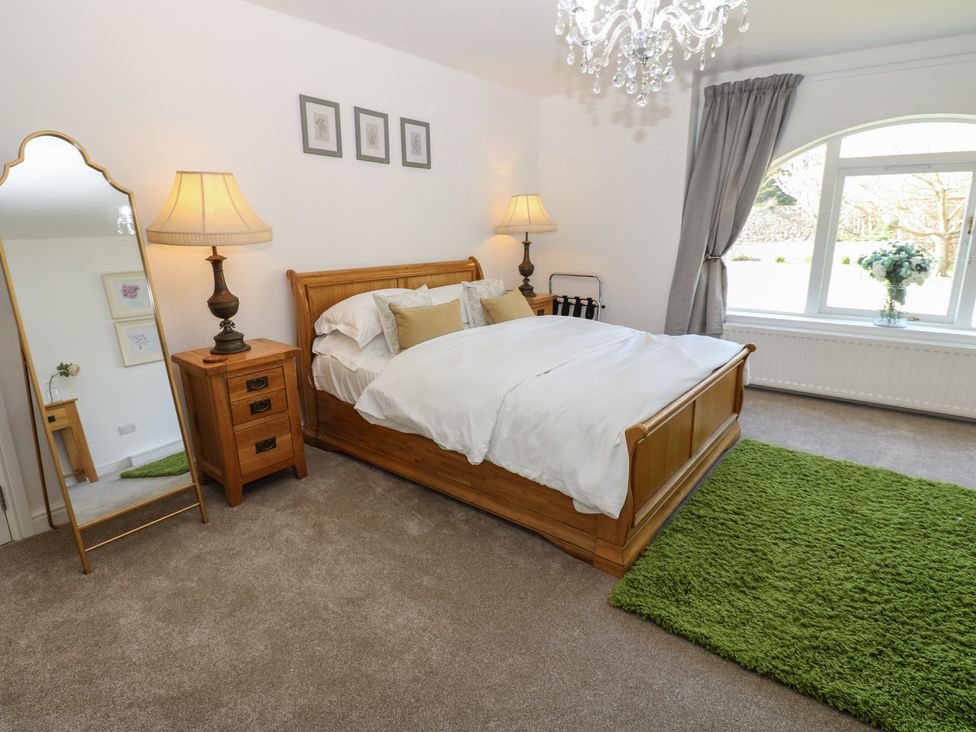 A bedroom with a bed, lamp, and a mirror at Castle View Cottage in Bedale