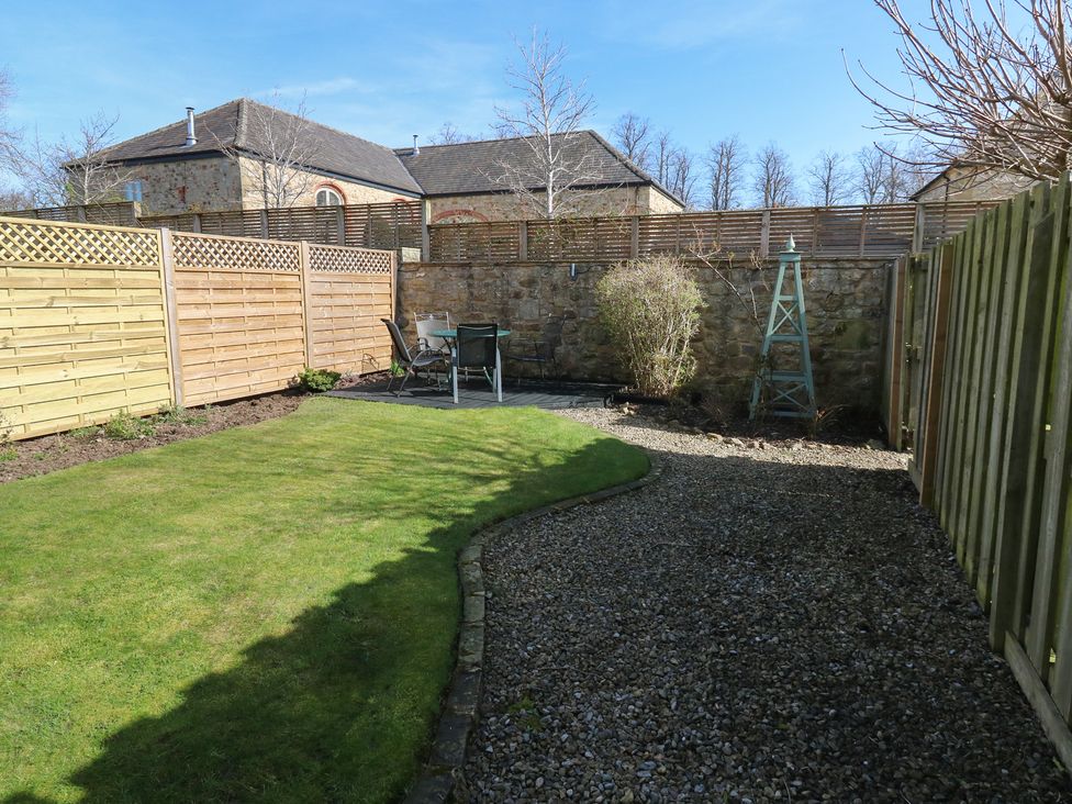A garden with grass, gravel path, and seating at Castle View Cottage Bedale