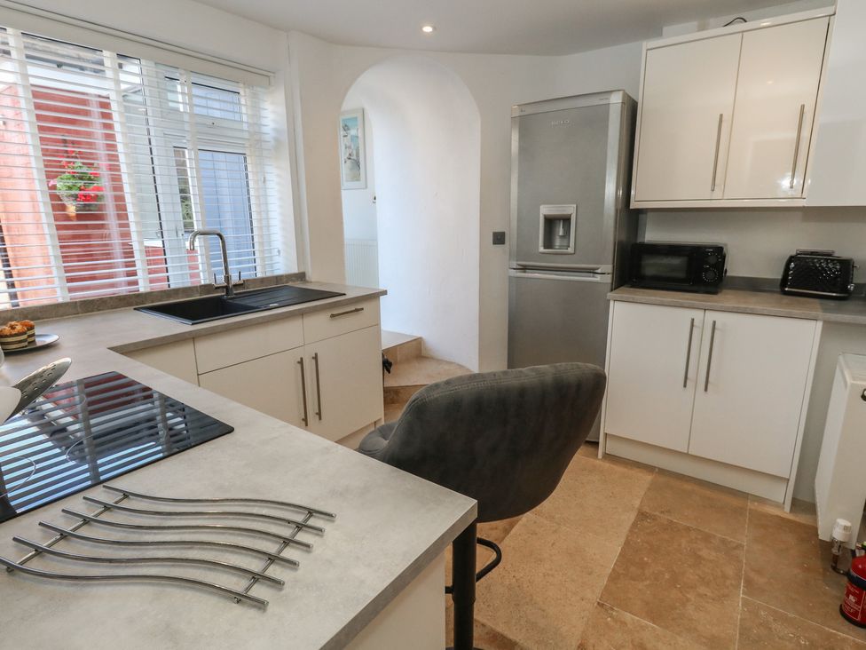A kitchen with sink, stove, refrigerator, and bar stool at Tipsy Turtle in Weymouth